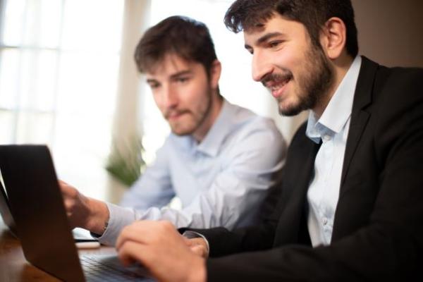 deux jeunes employés de bureau ou hommes d'affaires travaillent ensemble avec des ordinateurs portables