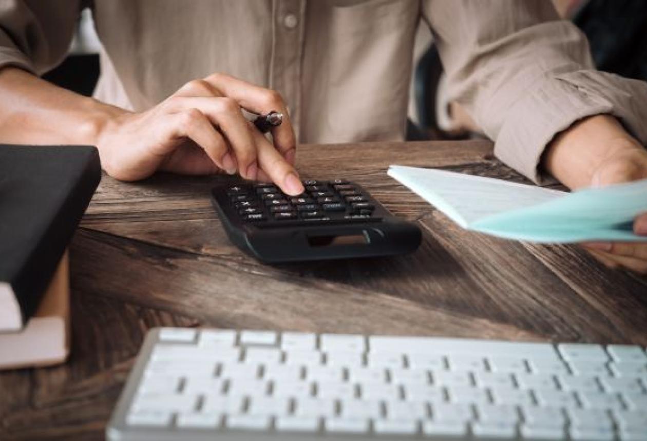 Vue rapprochée d'une femme d'affaires utilisant une calculatrice pour effectuer des calculs financiers. Concept de gestion des finances d'entreprise et de comptabilité.