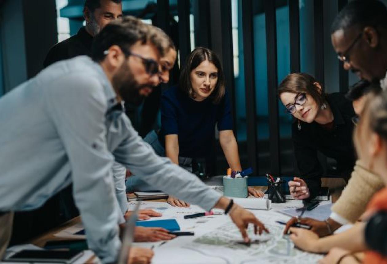 Manager et collaborateurs collaborant autour d’un écran affichant des modules de formation en ligne, symbolisant une culture d’apprentissage en entreprise